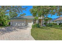Charming single-story home with a well-manicured lawn, mature trees, and a brick driveway at 4920 Woodhurst Dr, Sarasota, FL 34243
