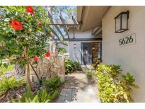 Inviting front entrance with a stone pathway, lush landscaping, and a pergola, leading to a glass-paneled front door at 5626 Pipers Waite # 22, Sarasota, FL 34235