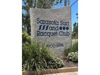 A welcome sign for Sarasota Surf and Racquet Club surrounded by landscaping and identifying the complex at 5916 Midnight Pass Rd # 404, Sarasota, FL 34242