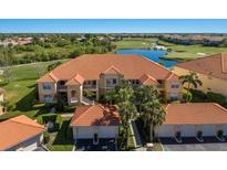 Beautiful condominium featuring a red tiled roof, tropical landscaping, and gorgeous golf course views at 7179 Boca Grove Pl # 202, Lakewood Ranch, FL 34202