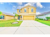 Inviting two-story home featuring a well-manicured lawn and attached two-car garage at 10944 Rainbow Pyrite Dr, Wimauma, FL 33598