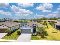 Inviting single-Gathering home featuring manicured lawn, mature landscaping and paver driveway with a water view in the background at 19801 Fishhawk Trl, Venice, FL 34293