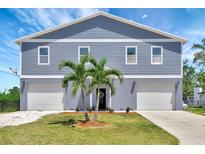 Charming two-story home featuring a double garage, well-manicured lawn, and decorative palm trees at 217 22Nd Street Ne Ct, Bradenton, FL 34208