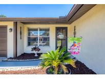 Charming front entrance with a welcome flag, decorative plants, and a window at 217 High Point Dr # 217A, Englewood, FL 34223