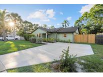 Charming single-story home with a concrete driveway, green lawn, and lush landscaping at 2915 Woodpine Cir, Sarasota, FL 34231