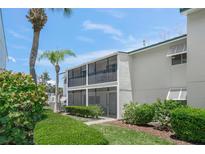 Exterior view of the building with a screened-in porch and tropical landscaping at 5681 Midnight Pass Rd # 104, Sarasota, FL 34242