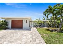 Charming single-story home featuring a well-manicured lawn, and paver driveway leading to the attached garage at 6841 Roxbury Dr, Sarasota, FL 34231