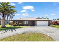 Charming single-story home featuring an attached two-car garage, palm tree, and well-maintained landscaping at 710 Beverly Rd, Venice, FL 34293