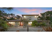 Charming home featuring a stone facade, red door, and lush, tropical landscaping at 8255 Longbay Blvd, Sarasota, FL 34243