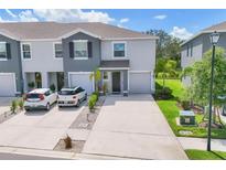 Two-story townhome features a gray facade, manicured lawn and driveway for two cars at 8628 Milestone Dr, Sarasota, FL 34238