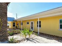 Charming yellow condo building featuring lovely landscaping with a sandy walkway leading to the unit at 105 Casey Key Rd # 20, Nokomis, FL 34275