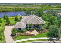 Stunning aerial view of a waterfront home with lush landscaping, tiled roof, and private dock on a tranquil waterway at 11807 Rive Isle Run, Parrish, FL 34219
