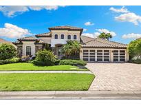 Beautifully landscaped front yard of a luxury home, showcasing a manicured lawn and a three-car garage at 2152 Majestic Oaks Blvd, Clearwater, FL 33759