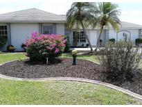 Landscaped front yard featuring vibrant flowers, palm trees, and a well-maintained lawn at 2178 Calcutta Rd, Punta Gorda, FL 33983