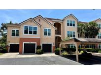 Charming condo building with a Spanish-tile roof, attached garages, and assigned carport parking at 4142 Central Sarasota Pkwy # 1423, Sarasota, FL 34238