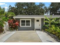 Inviting front exterior showcasing lush tropical landscaping, enhanced by a well-maintained lawn and concrete driveway at 4695 86Th N Ave, Pinellas Park, FL 33782