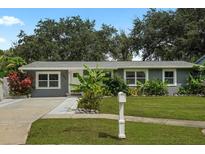 Charming single-story home featuring a well-manicured lawn, complemented by lush tropical landscaping in the front yard at 4695 86Th N Ave, Pinellas Park, FL 33782