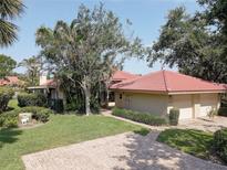 Charming home exterior boasting a lush front yard, red tile roof, and convenient two-car garage at 5039 Kestral Park Dr # 67, Sarasota, FL 34231