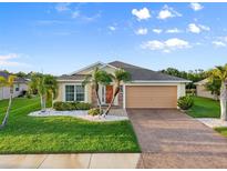 Inviting single-story home featuring lush lawn, palm trees, and a neutral color palette at 5902 106Th E Ter, Parrish, FL 34219