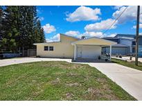 Charming single-story home with a covered carport and well-maintained front lawn on a sunny day at 7308 Maryland Ave, Hudson, FL 34667