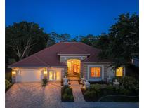 Stunning exterior view of home with landscaped front yard, brick driveway, and beautiful roofline at twilight at 766 Shadow Bay Way, Osprey, FL 34229