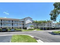 Lovely three-story condo with carports and tropical landscaping against a bright blue sky at 8735 Olde Hickory Ave # 8205, Sarasota, FL 34238