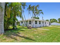 Charming single-story home featuring a well-maintained lawn, beautiful palm trees, and a welcoming facade at 1200 25Th W Ave, Palmetto, FL 34221