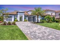Beautifully landscaped home with a paved driveway and a two-car garage and a lush green lawn at 12005 Trails Reserve Ct, Sarasota, FL 34238