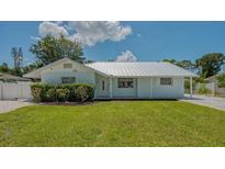 Charming single-story home featuring a well-manicured lawn, fresh landscaping, and a durable silver metal roof at 1461 Porpoise Rd, Venice, FL 34293