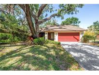Charming single-story home with a red garage door, mature trees, and a spacious driveway at 3934 Brookside Dr, Sarasota, FL 34231