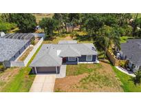 Aerial view of a well-maintained home with a gray roof, green lawn, and mature trees in a desirable neighborhood at 4664 Hegira St, North Port, FL 34286