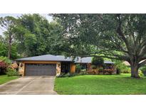 Charming home featuring a stone facade, two-car garage, and inviting curb appeal with mature landscaping at 4873 Huntleigh Dr, Sarasota, FL 34233