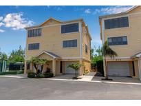 Inviting two-story yellow home with a well-maintained yard and attached garage at 603 Cedars Ct, Longboat Key, FL 34228