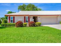 Charming home with a well-manicured lawn, red shutters, and a bright white tile roof at 6701 12Th W Ave, Bradenton, FL 34209