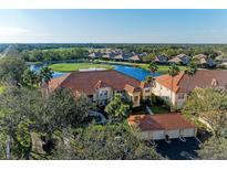 Elegant condo building featuring a terracotta roof with scenic views overlooking a lush golf course and serene lake at 8422 Wethersfield Run # 103, Lakewood Ranch, FL 34202