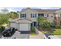 Charming townhome with a two-car garage, complemented by a well-maintained lawn and colorful blue door and window trim at 8926 Manor Loop # 201, Lakewood Ranch, FL 34202
