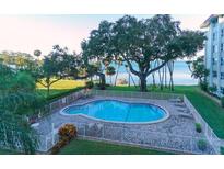 A picturesque pool with bay views surrounded by mature trees, lounge chairs, and white picket fence at 1100 Imperial Dr # 507, Sarasota, FL 34236
