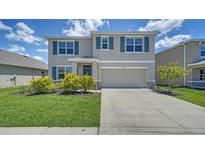 Charming two-story home with a well-manicured lawn and inviting curb appeal, featuring blue shutters at 12728 Lateral Root Dr, Sarasota, FL 34238