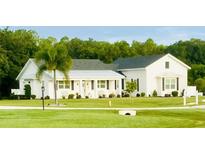 Charming white farmhouse style home with a well-manicured lawn and mature landscaping at 17605 Roanwood Ct, Parrish, FL 34219