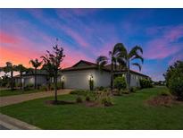Charming single-story home with a two-car garage, lush landscaping, and a brick-paved driveway at sunset at 17725 Northwood Pl., Bradenton, FL 34202