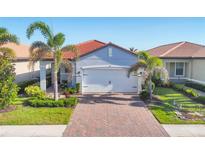 Charming single-story home with a red tile roof, lush landscaping, and a brick driveway at 197 Villoresi Blvd, Nokomis, FL 34275