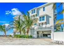 Three-story beach house featuring white exterior, palm trees, an open garage, and a private entrance at 2500 Gulf N Dr, Bradenton Beach, FL 34217