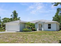 Charming single-story home featuring a well-maintained lawn, a two car garage, and decorative plants at 2575 Johannesberg Rd, North Port, FL 34288