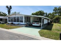 Charming manufactured home featuring a carport and a cozy sunroom enclosed with large awning style windows at 3308 Oakwood S Blvd, Sarasota, FL 34237