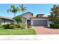 Charming one-story home featuring a tile roof, a two-car garage, and tropical landscaping, offering great curb appeal at 5968 Snowy Egret Dr, Sarasota, FL 34238