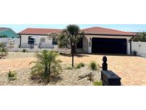 Charming single-story home with a red tile roof, lush landscaping, and a brick-paved driveway at 6524 Senegal Palm Way, Apollo Beach, FL 33572
