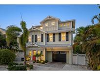 Charming two-story home with a black garage door and a landscaped yard, creating an inviting curb appeal at 704 Gladiolus St, Anna Maria, FL 34216
