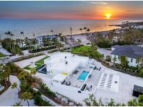 Stunning aerial view of a modern white home with a pool, beachfront access and sunset views at 7647 Sanderling Rd, Sarasota, FL 34242