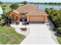 Charming home boasts a well-manicured lawn, lush landscaping, and a view of the golf course and lake at 834 Springwood Cir, Bradenton, FL 34212