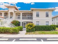 Inviting condo exterior with manicured landscaping, tile roof and staircase leading to second floor at 10202 L Pavia Blvd # 10202, Venice, FL 34292
